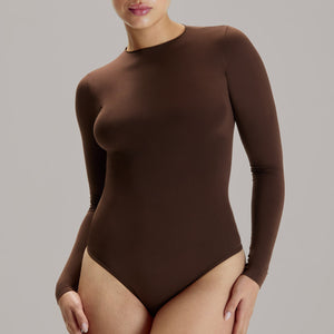 Modelo usando body manga larga cuello alto para mujer color chocolate de Lunia, vista frontal.