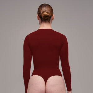 Modelo usando body manga larga cuello alto para mujer color vinotinto de Lunia, vista trasera.