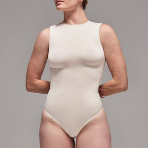 Modelo usando body sin manga cuello alto para mujer color marfil de Lunia, vista frontal.