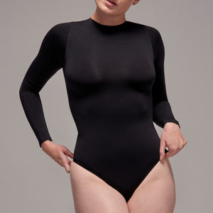 Modelo usando body manga larga cuello alto para mujer color negro de Lunia, vista frontal.  