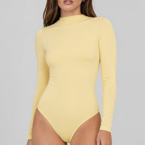 Modelo usando body manga larga cuello alto para mujer color amarillo de Lunia vista delantera 